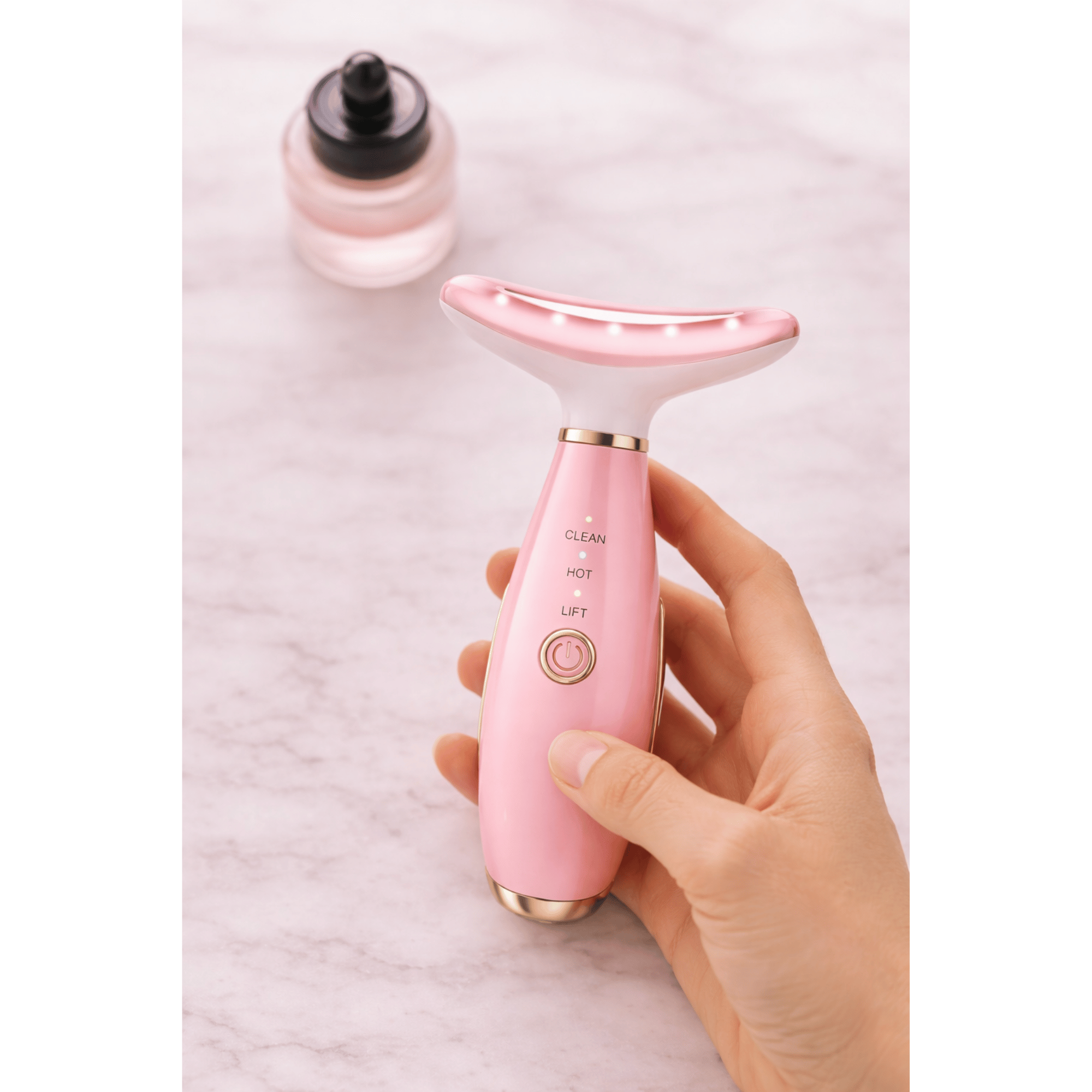 Pink electronic device held by a hand with a bottle in the background