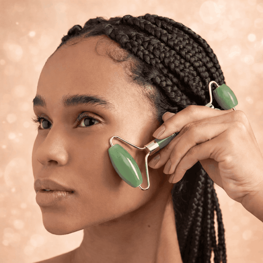 Woman using a green facial roller on her face against a beige background