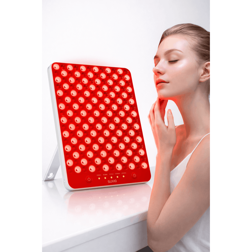 Woman using a red light therapy device on her face
